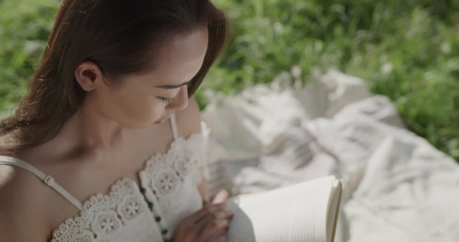 A woman reading a book on a blanket