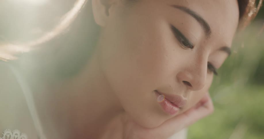 Asian woman in a revealing shirt resting her hand on her chin and thinking