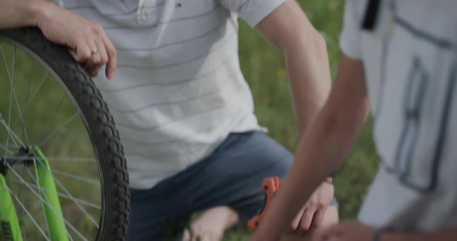 Father showing his son explaining how to fix a bicycle chain and letting his son fix it