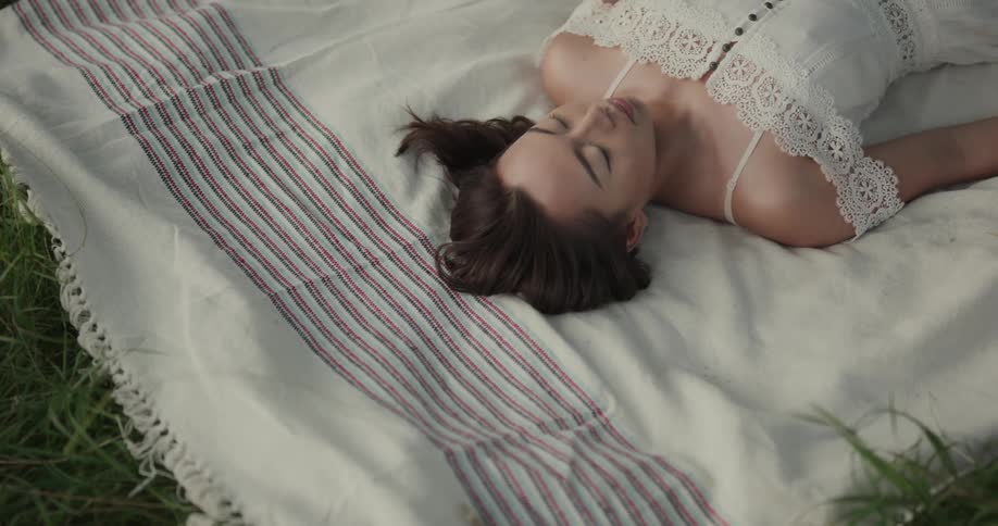 A young woman sleeping on a blanket outside