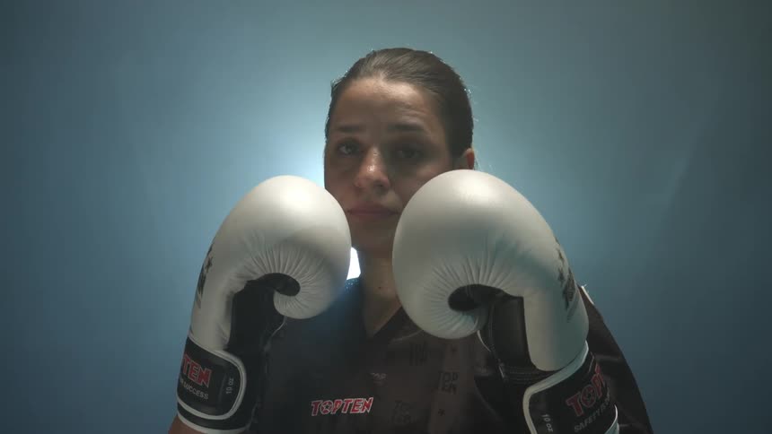Woman wearing boxing gloves lifts up her hands