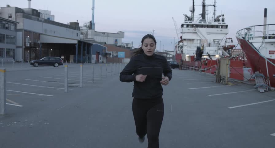 A woman in black runs in a parking lot