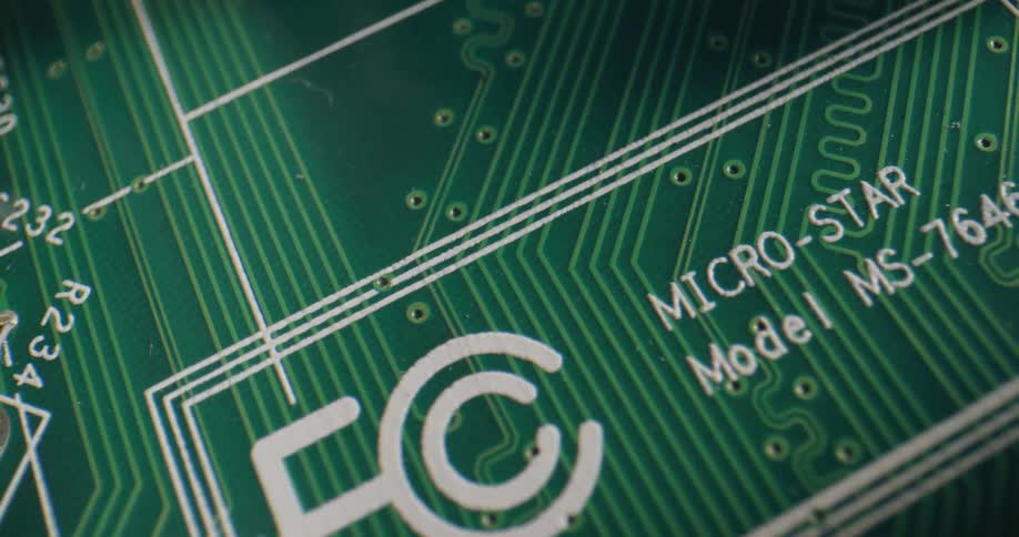 A green circuit board with metal and black components and white black and red text