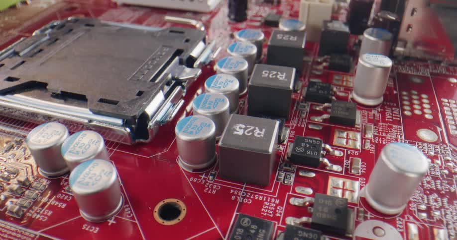 A close up of a red circuit board with metal and plastic pieces and white letters and numbers