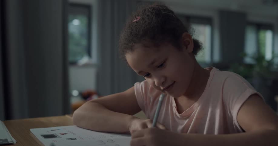 Young girl doing homework on a table in a room at home