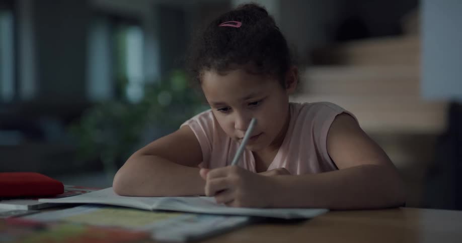 Young girl doing homework on the table in a room at home