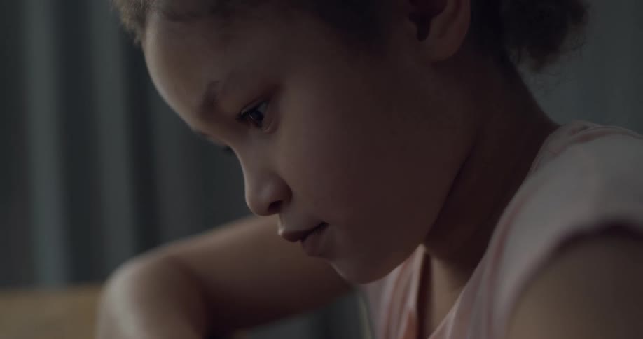 A girl sits at a table indoors working on something