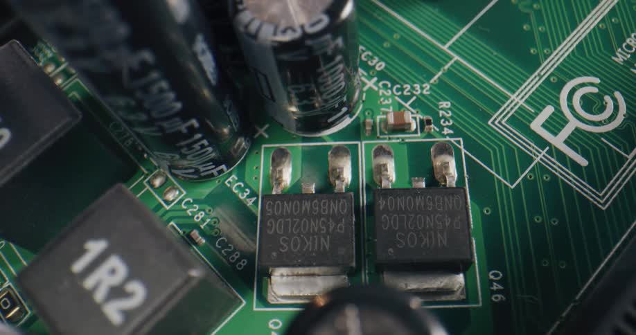 A green circuit board with black and metal components and gray letters and numbers