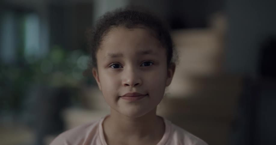 Girl with pink shirt faces the camera with eye contact