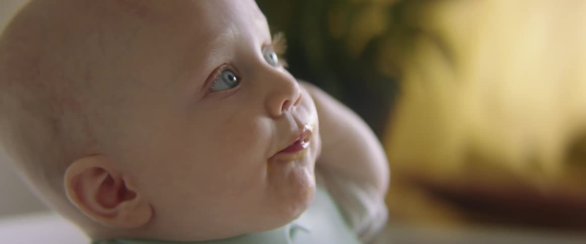 A person feeding a baby food from a spoon