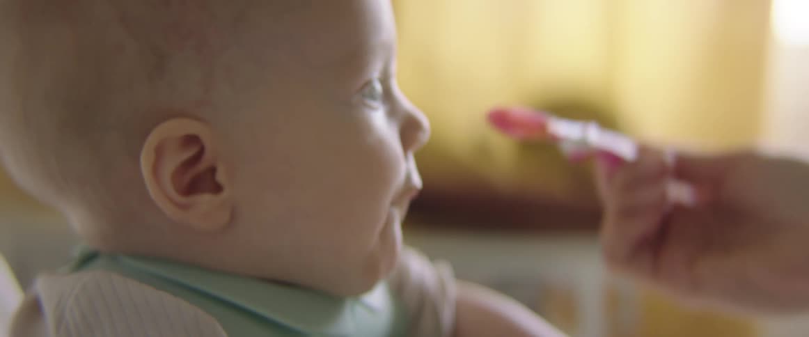 A woman spoon feeding her baby at home