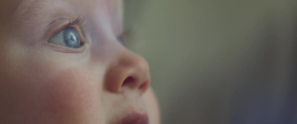 The hand of an adult reaches up to rub the cheek of a baby