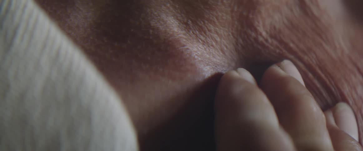 An elderly woman rubs her skin under her neck