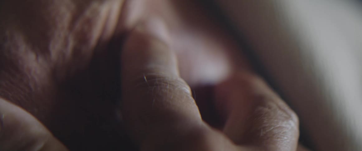An elderly woman touches and rubs her chest just below her neck