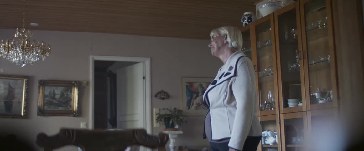 Senior woman enters the dimly lit living room and stands waiting