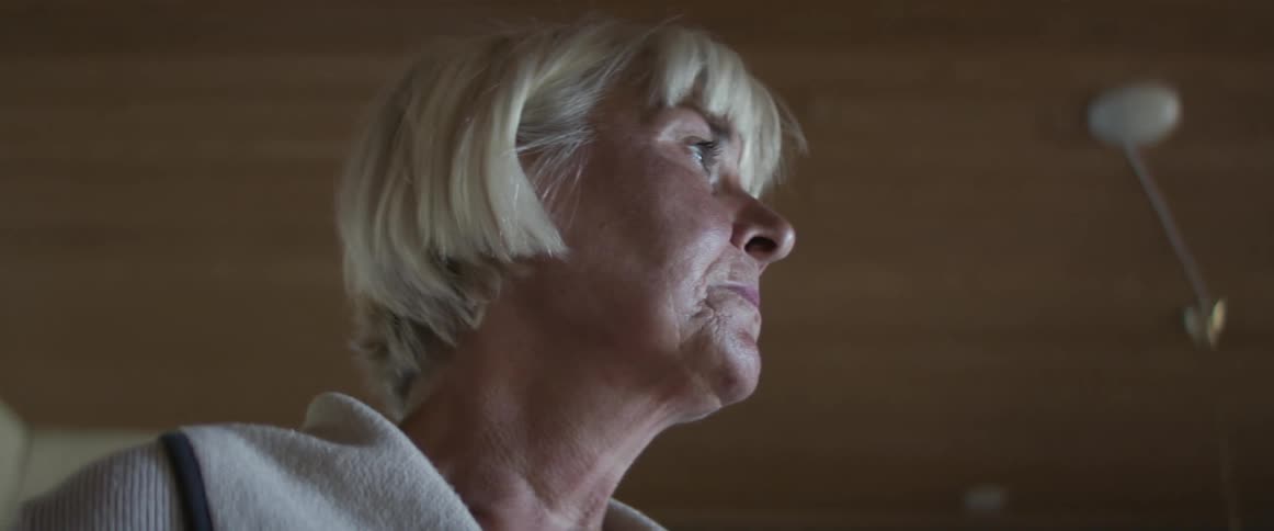 Side view of an elderly woman wiping tears with her hand
