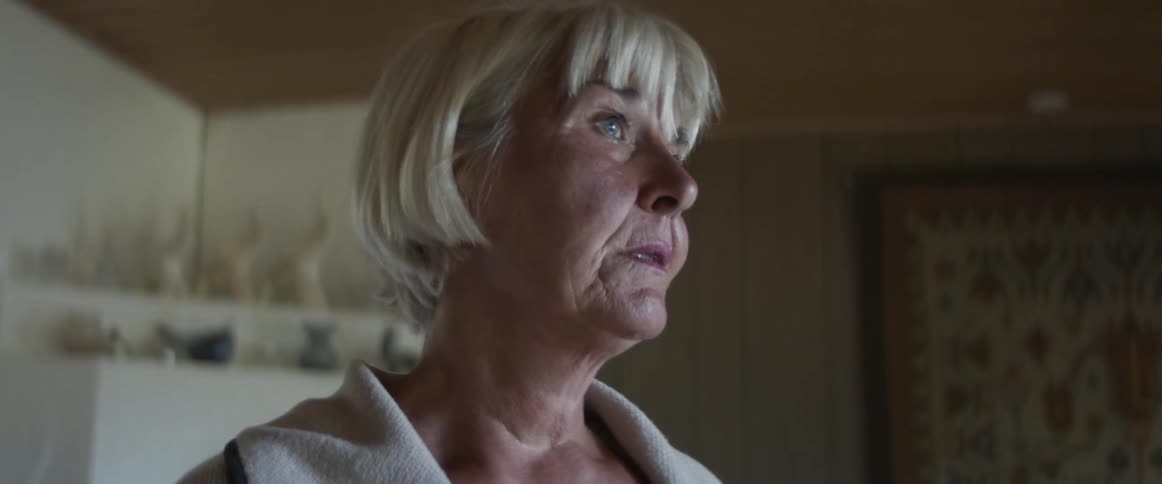 Senior woman standing in the living room at home dries a tear from her face with her fingers
