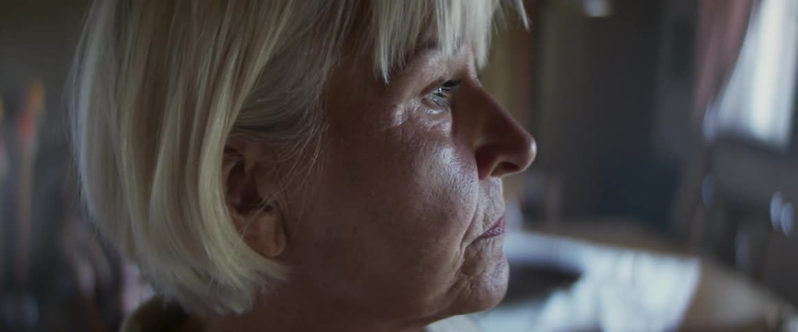 Side view of an elderly woman with wrinkles and grey hair in dining room