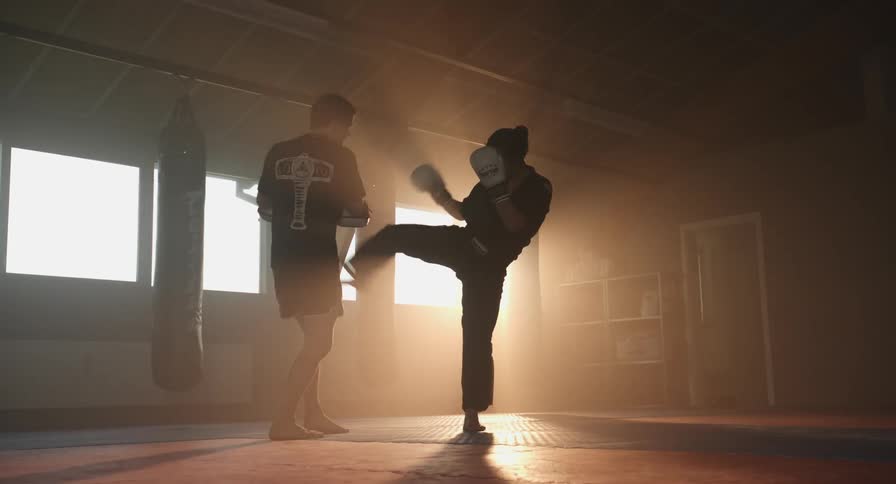 Two people are sparring in a gym
