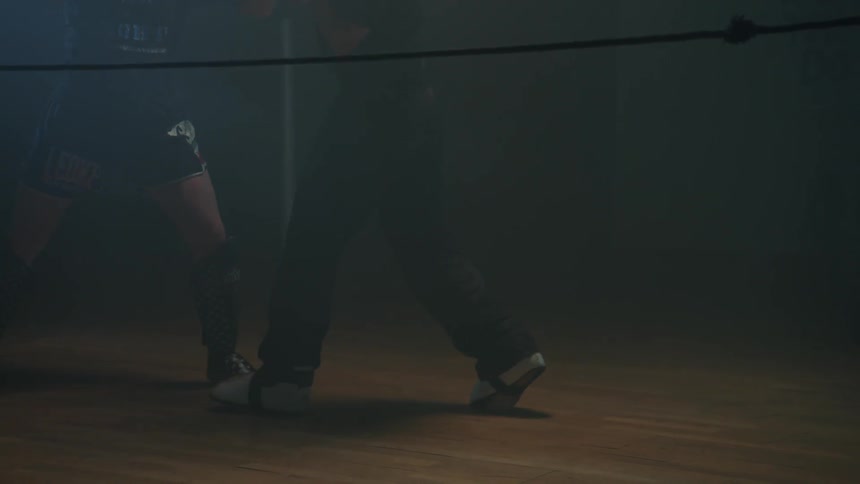 Two people boxing in a dimly lit ring
