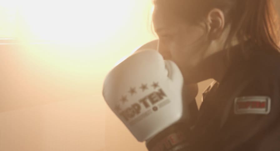 A woman wearing boxing gloves punches a punching bag