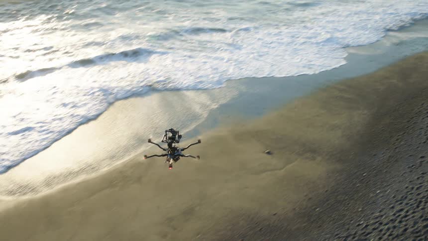 Tilt down tracking shot of a drone flying over a beautiful beach as waves wash ashore