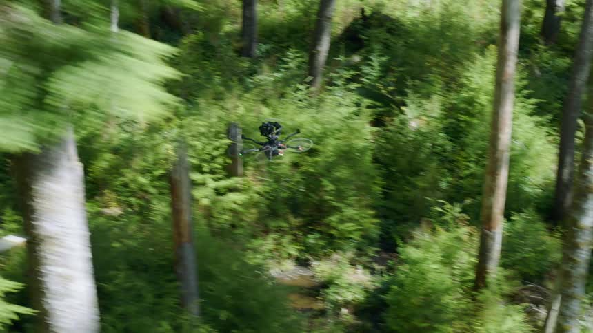 Parallel traverse of a multi rotor drone flying quickly through forest trees at daytime