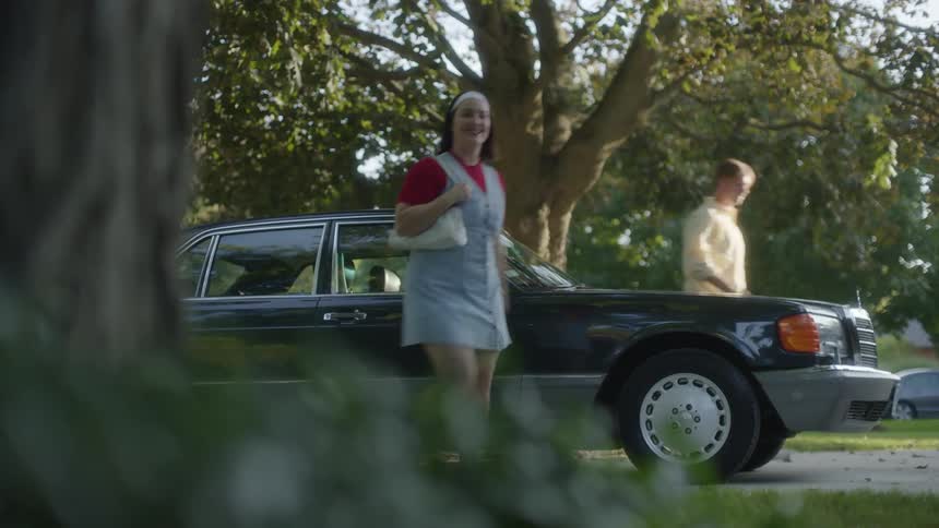 A young girl runs out of a parked vehicle excitedly as her parents walk behind her