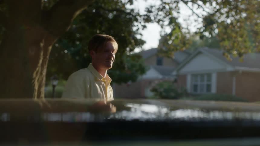 A white man exits a car and walks to a house in a neighborhood during the day
