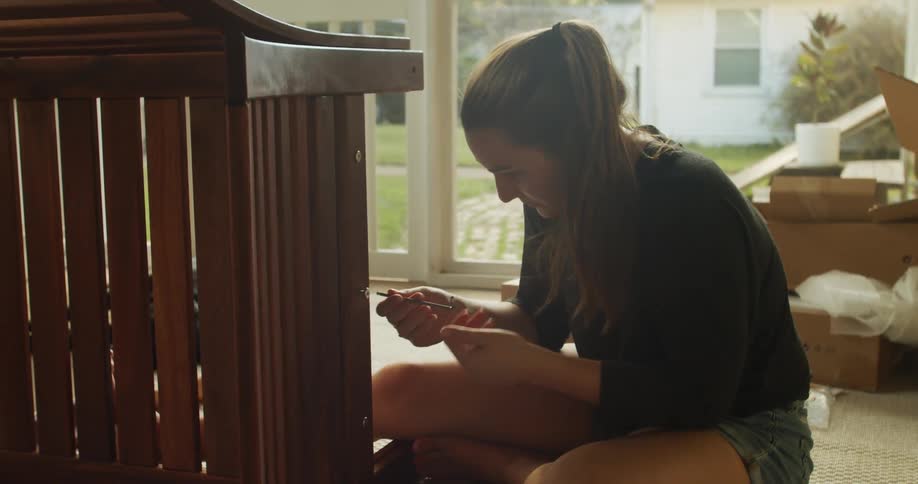 A woman is building a crib in the bedroom