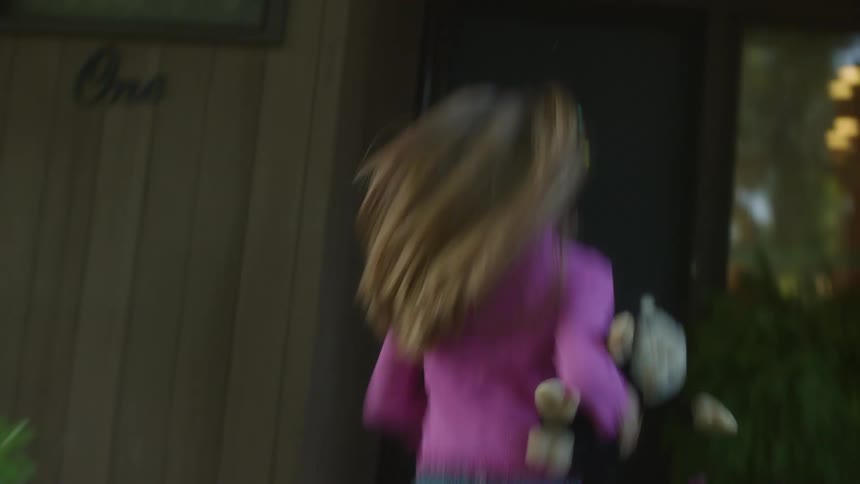 Young girl carrying a stuffed animal playfully runs inside the house