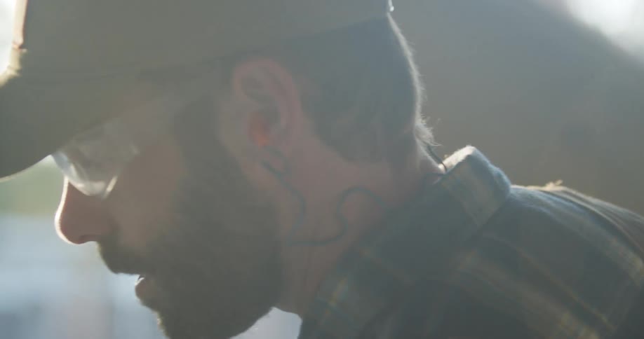 A man wears safety protection on eyes and ears while working outdoors