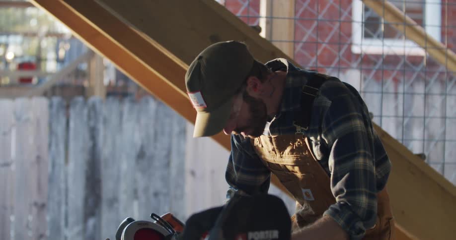Carpenter measuring a piece of wood before cutting outdoors at sunset