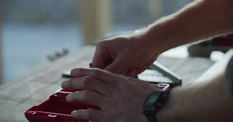A person with a wristwatch taking a drill bit from a tool case