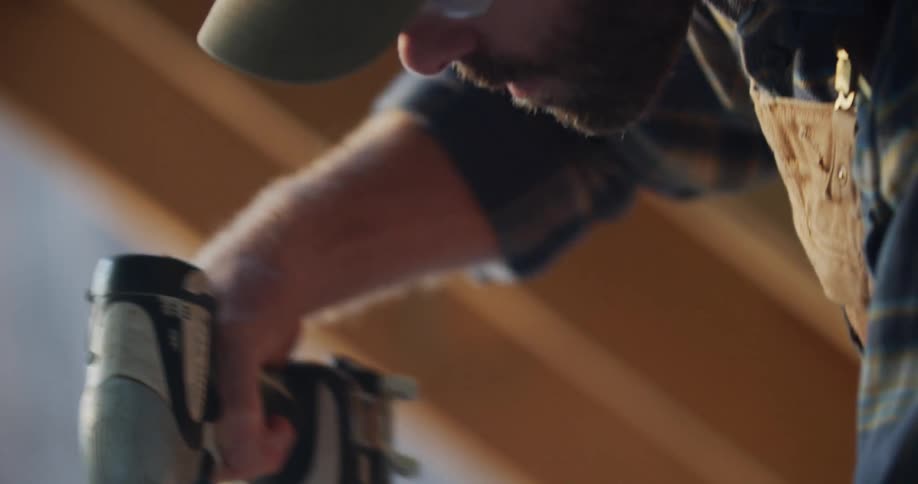 A man drills a hole in to wood and then blows the sawdust off