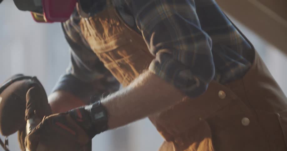 A man sands wood with an electric sander