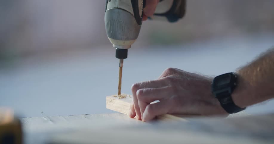 A man drilling a hole through a piece of wood