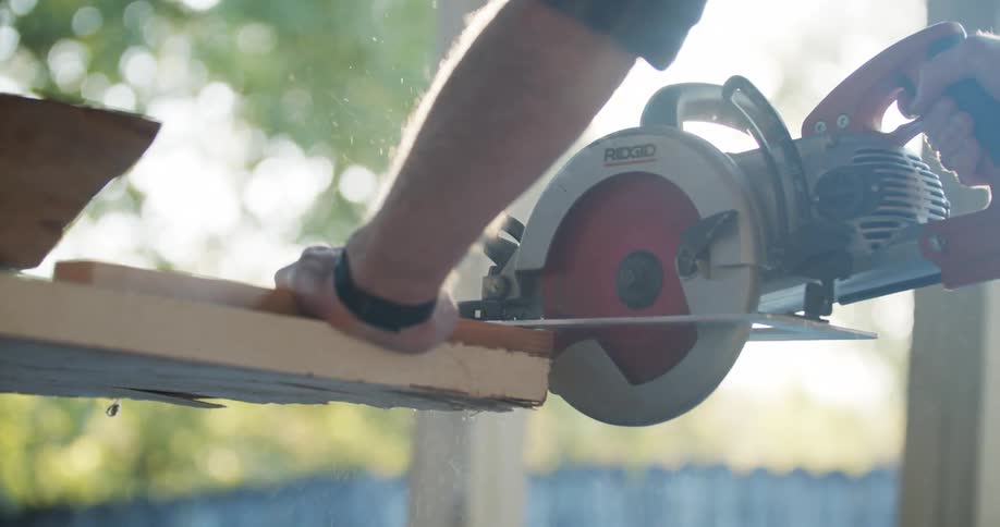 A man uses a circular saw to cut a piece of wood