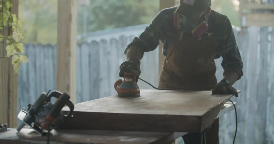 A man in a back yard sanding wood
