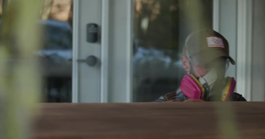 A man sand wood furniture outside of a house
