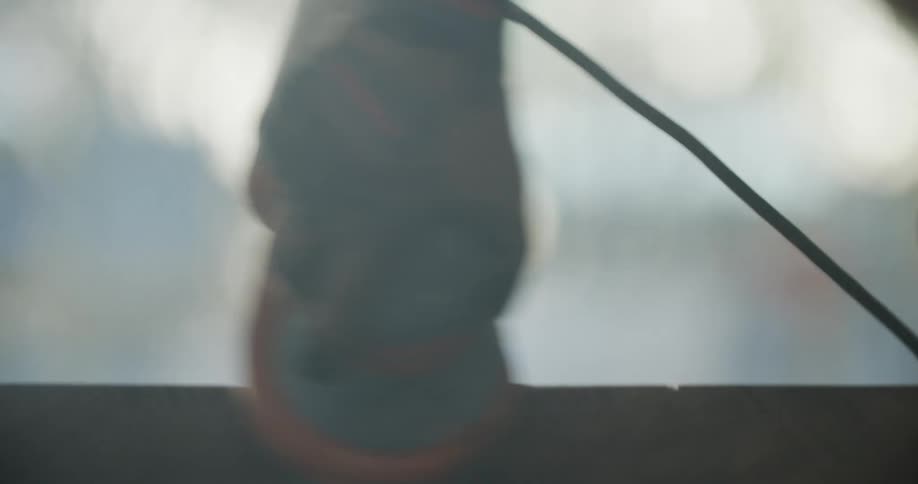 A man uses a power sander on a piece of wood while wearing personal protective equipment