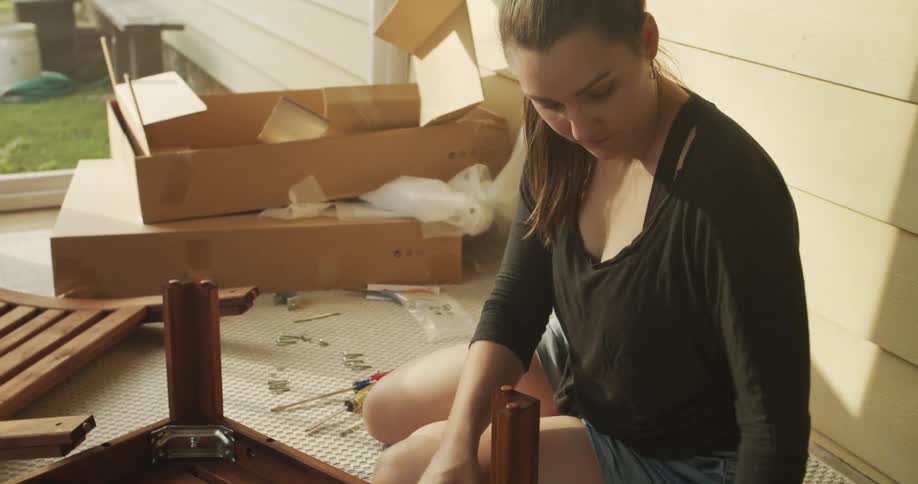 Woman outside on the porch building a table from the instructions