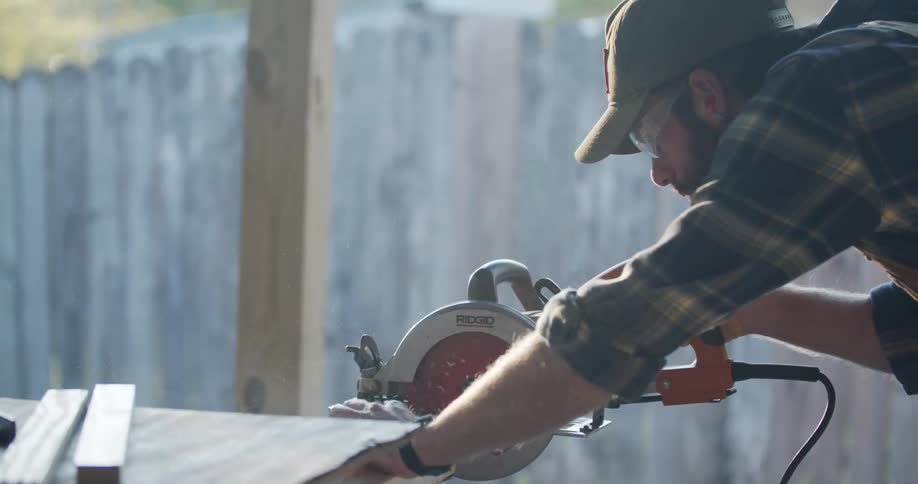 A man cuts a piece of wood with a circular saw