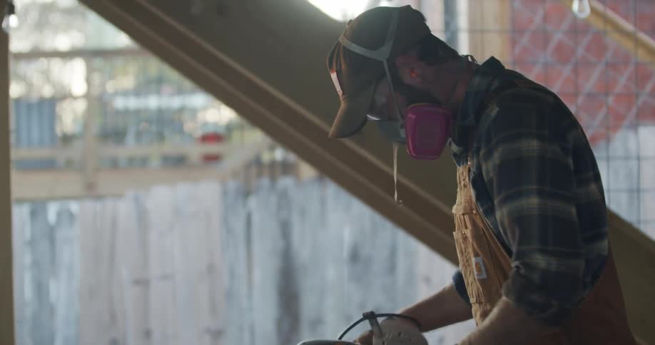 A man is at a wooden table pulling a saw out of a bag