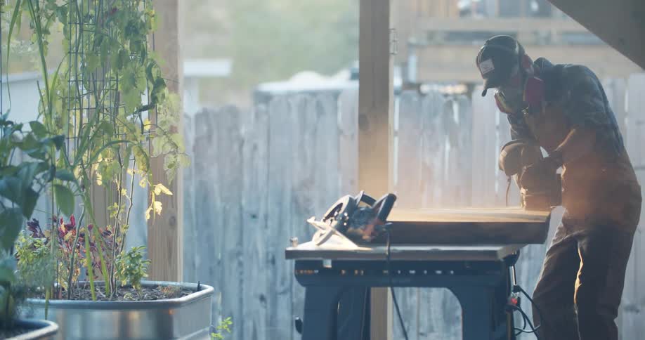 A man is sanding a board on the construction site