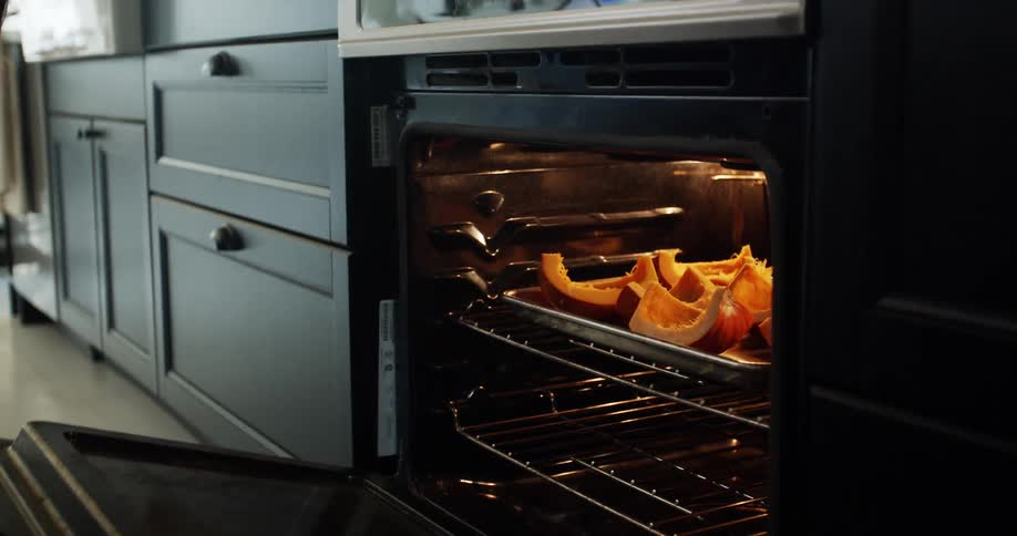 A woman cooking at home closes the oven door