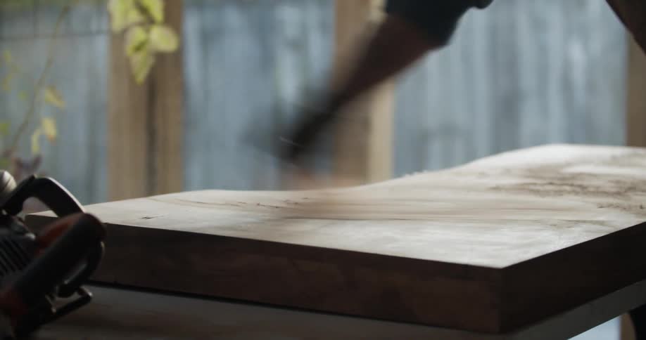 A man brushes sawdust off a piece off wood