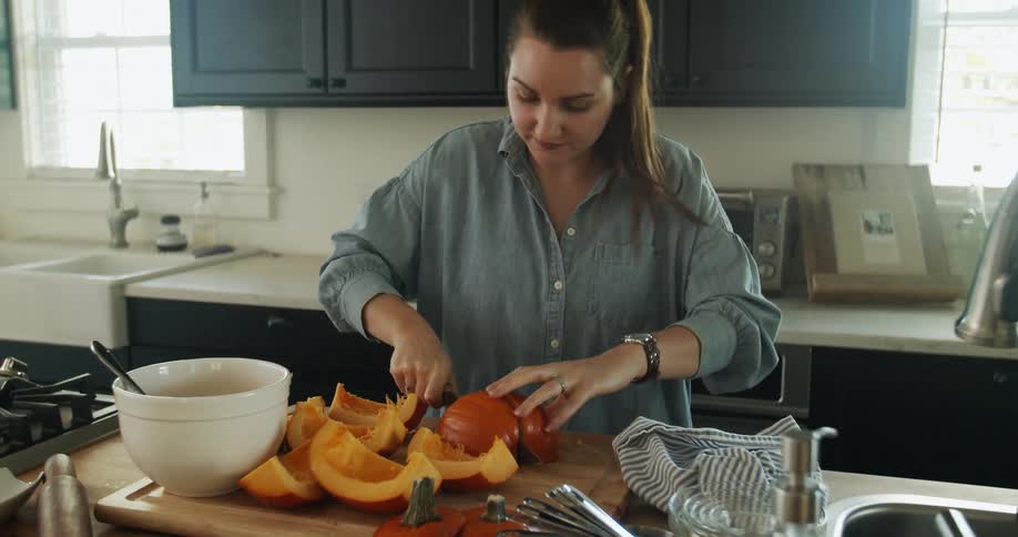 Woman cutting up a pumpkin in a kitchen
