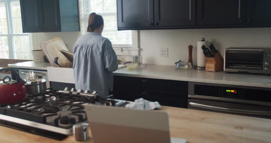 A caucasian woman cleaning up the kitchen and washing dishes