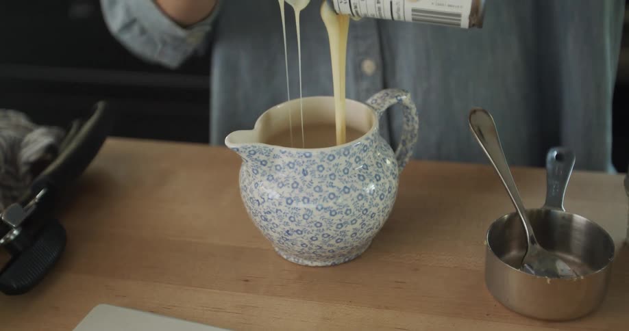 A woman pours liquid as she bakes at home